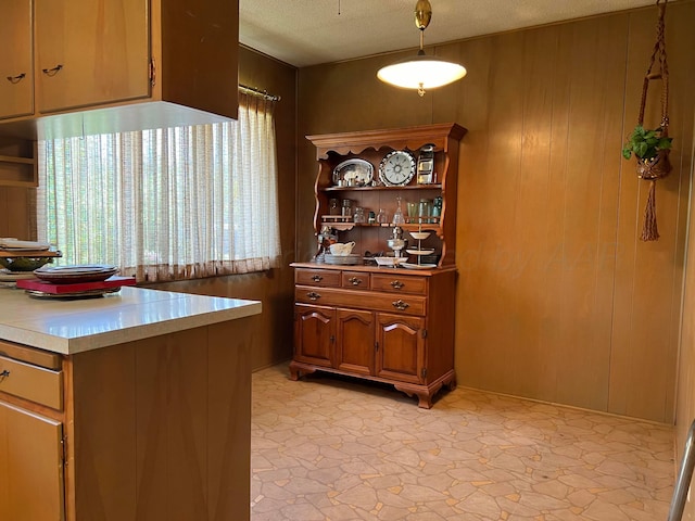 kitchen with wooden walls, pendant lighting, and a textured ceiling