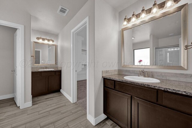 9110 Lexford Dr, Amarillo, TX 79119 - bathroom featuring two vanities, wood finished floors, and a spacious closet