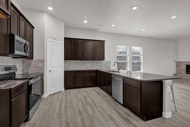9110 Lexford Dr, Amarillo, TX 79119 - kitchen featuring appliances with stainless steel finishes, a peninsula, dark stone countertops, tasteful backsplash, and dark brown cabinets