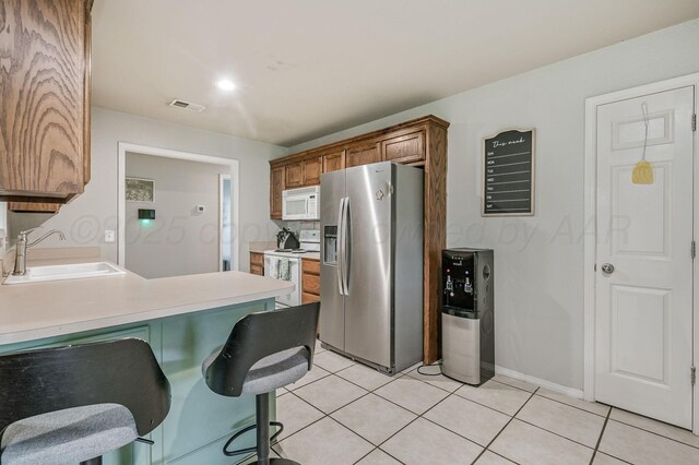 2002 SW 61st Ave, Amarillo, TX 79118 - kitchen with white appliances, a sink, light countertops, light tile patterned floors, and a kitchen bar
