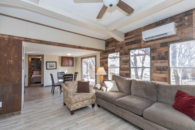 living room with a healthy amount of sunlight, light wood-type flooring, an AC wall unit, and beam ceiling