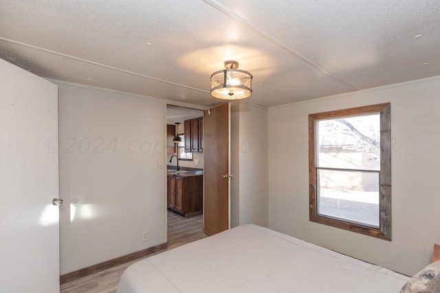 bedroom featuring sink, a textured ceiling, and light hardwood / wood-style flooring