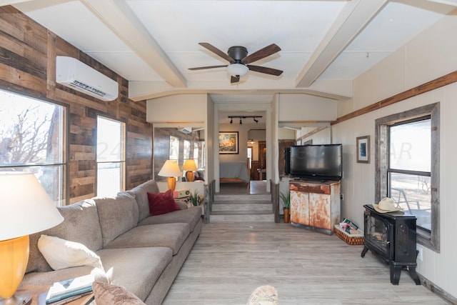 living room featuring a wood stove, wooden walls, beam ceiling, light hardwood / wood-style flooring, and an AC wall unit