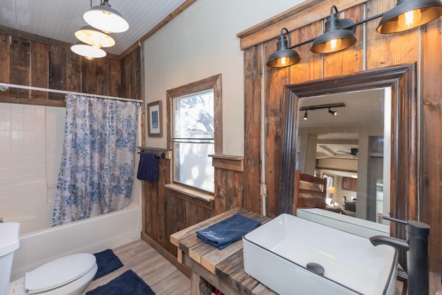 bathroom featuring wood walls, hardwood / wood-style flooring, ornamental molding, shower / bathtub combination with curtain, and toilet