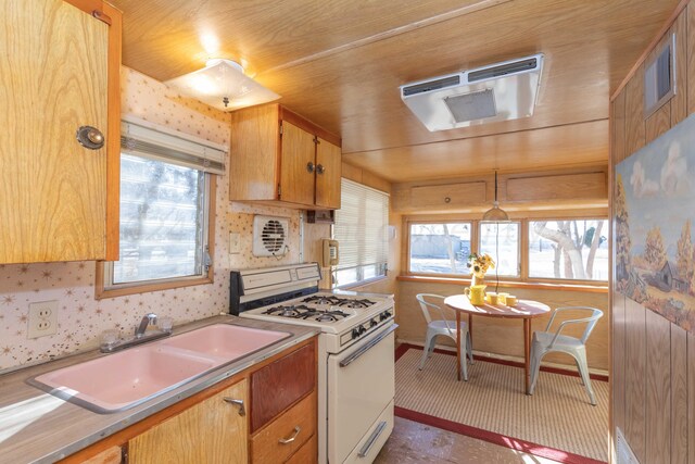 kitchen with white gas range, sink, and wood ceiling