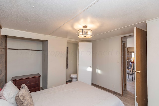 bedroom featuring hardwood / wood-style flooring, a textured ceiling, a closet, and ensuite bathroom