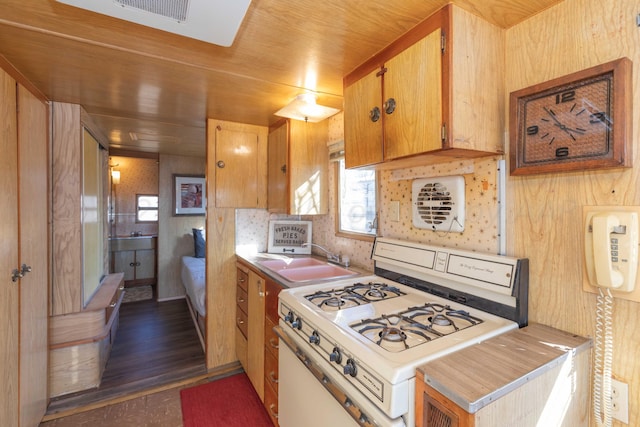 kitchen featuring wood walls, dark hardwood / wood-style flooring, sink, and white range with gas stovetop