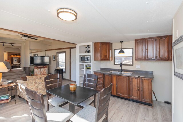 dining area featuring light wood-type flooring, sink, and ceiling fan