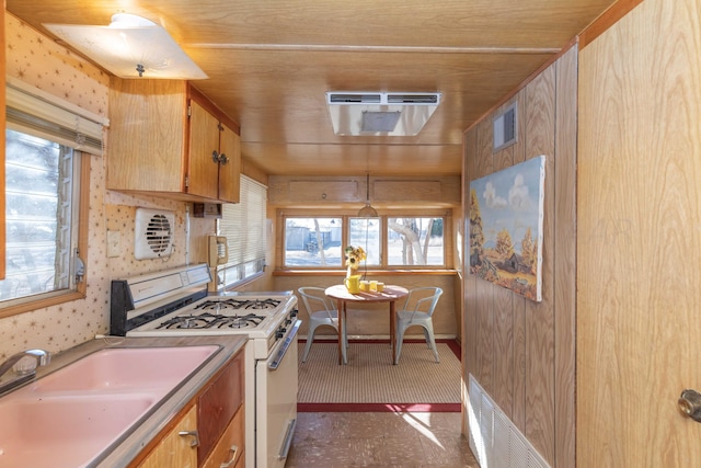 kitchen featuring wood walls, sink, and white gas stove