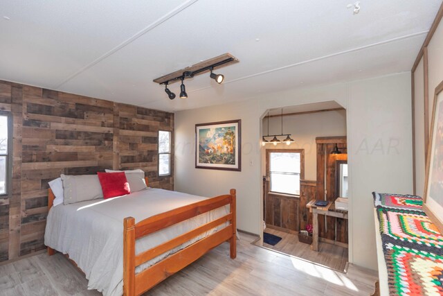 bedroom with light hardwood / wood-style flooring and wood walls