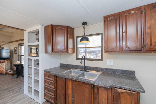 kitchen featuring decorative light fixtures, sink, and light hardwood / wood-style flooring