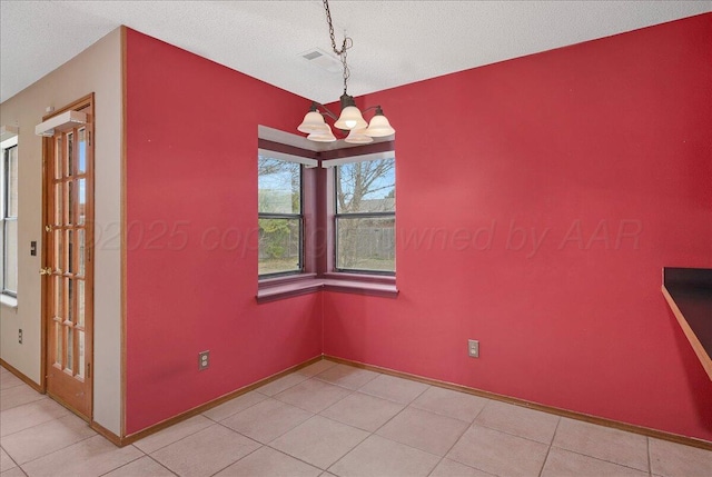 unfurnished dining area with light tile patterned flooring, a textured ceiling, and a notable chandelier