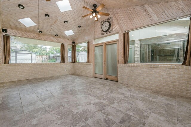 613 Bennett Dr, Dumas, TX 79029 - spare room featuring a skylight, high vaulted ceiling, brick wall, a ceiling fan, and stone finish floors