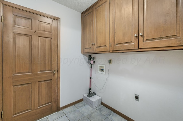 613 Bennett Dr, Dumas, TX 79029 - laundry room with cabinet space, hookup for an electric dryer, washer hookup, baseboards, and light tile patterned flooring
