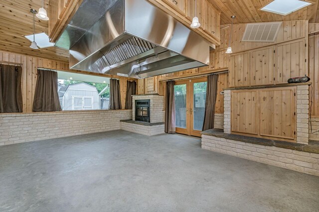 613 Bennett Dr, Dumas, TX 79029 - unfurnished living room featuring concrete floors, wood walls, a skylight, french doors, and a fireplace