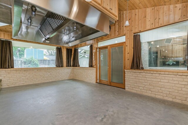 613 Bennett Dr, Dumas, TX 79029 - unfurnished living room with brick wall, wooden walls, and concrete floors