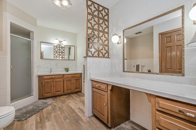 613 Bennett Dr, Dumas, TX 79029 - full bath with wood finished floors, a shower stall, vanity, toilet, and a textured ceiling