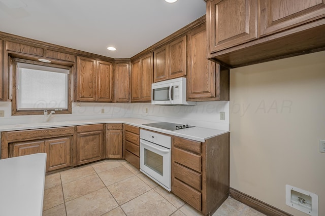 kitchen with white appliances, brown cabinets, light countertops, a sink, and light tile patterned flooring