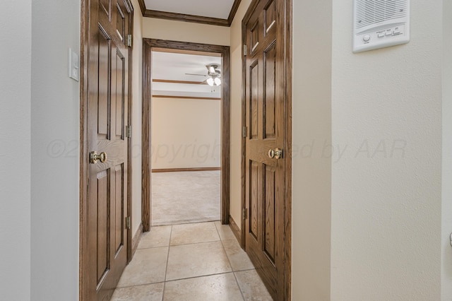 corridor with light carpet, baseboards, ornamental molding, and light tile patterned flooring