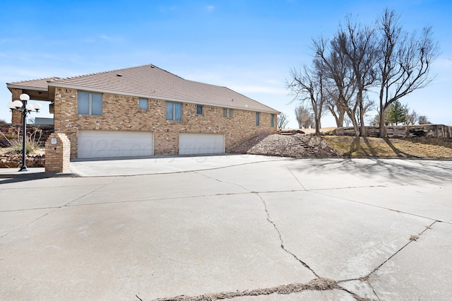 view of side of home with a garage, concrete driveway, and brick siding