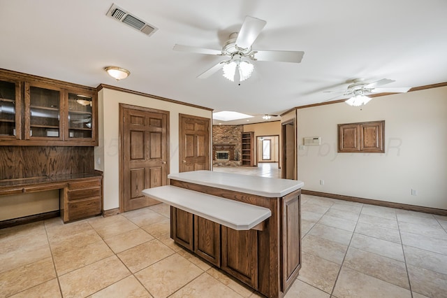 kitchen with light tile patterned floors, visible vents, built in desk, and ornamental molding