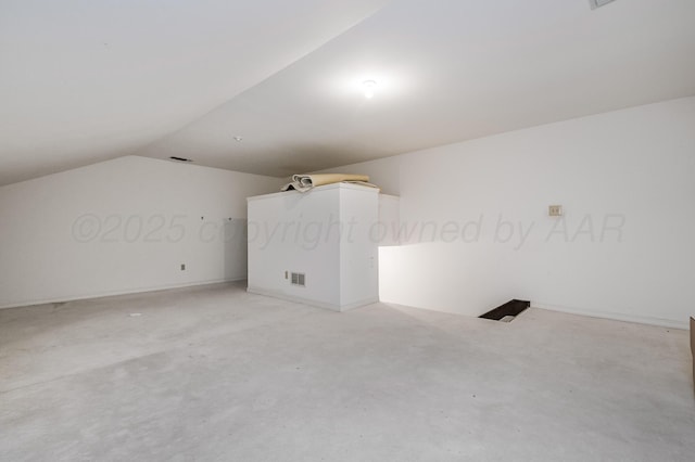 bonus room featuring concrete floors, visible vents, and vaulted ceiling