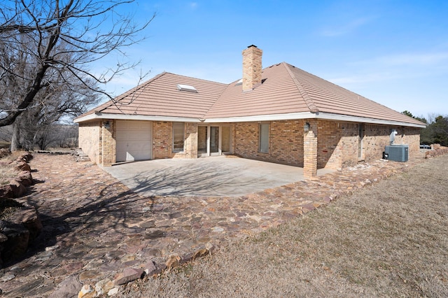 back of property with a patio area, brick siding, a chimney, and central air condition unit