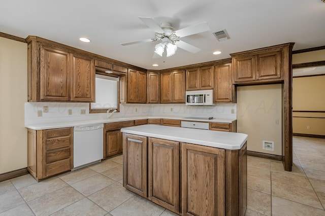 kitchen with brown cabinetry, light countertops, white appliances, and visible vents