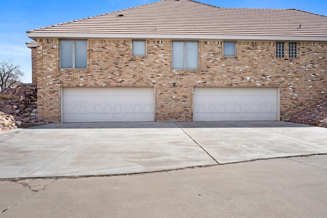 view of front of home featuring a garage, concrete driveway, and brick siding