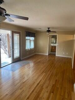 2237 Locust St, Amarillo, TX 79109 - unfurnished living room featuring a ceiling fan, baseboards, and wood finished floors