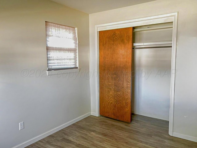 unfurnished bedroom with dark hardwood / wood-style floors and a closet