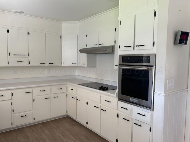 1610 Jordan St, Amarillo, TX 79106 - kitchen with oven, black electric stovetop, under cabinet range hood, dark wood-style floors, and light countertops