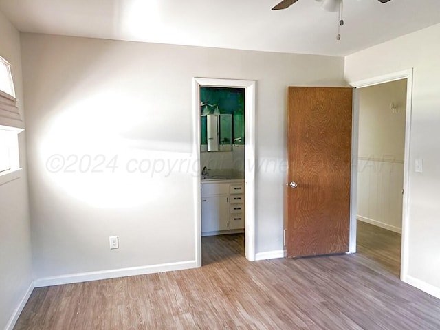 unfurnished bedroom with ensuite bath, a walk in closet, light hardwood / wood-style flooring, and ceiling fan