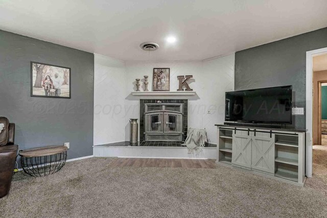15 Fannin Dr, Tulia, TX 79088 - carpeted living room featuring a wood stove and baseboards