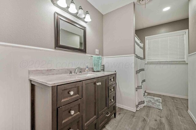 15 Fannin Dr, Tulia, TX 79088 - full bath featuring wood finished floors, vanity, and a shower with shower curtain