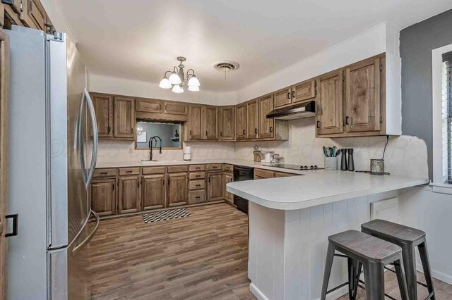 15 Fannin Dr, Tulia, TX 79088 - kitchen with black appliances, a peninsula, under cabinet range hood, decorative backsplash, and a sink