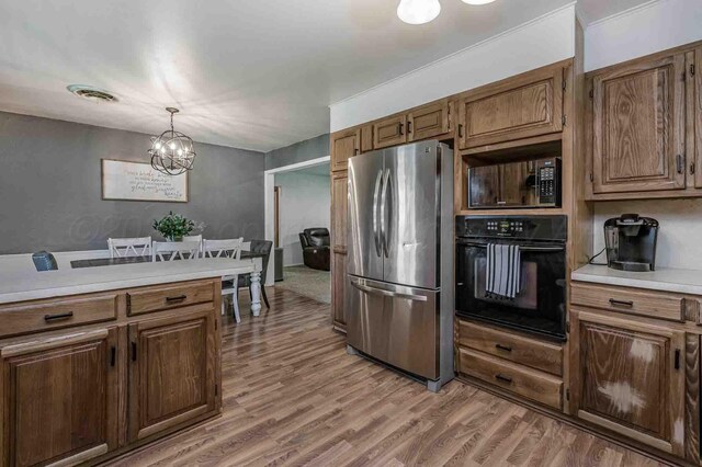 15 Fannin Dr, Tulia, TX 79088 - kitchen featuring black appliances, a chandelier, light countertops, light wood-style flooring, and hanging light fixtures
