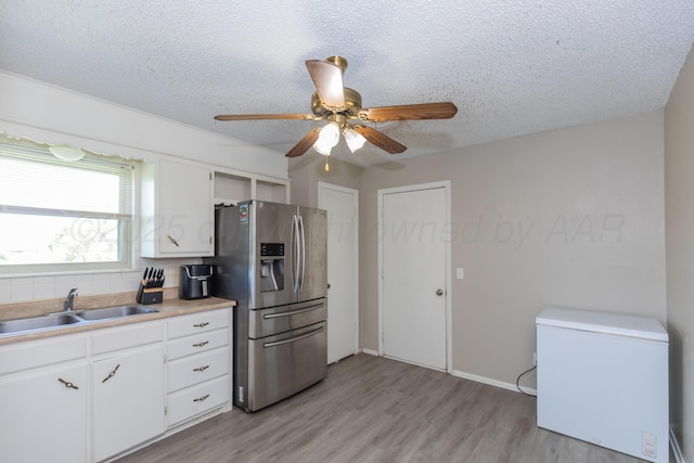 707 N Arkansas St, Shamrock, TX 79079 - kitchen featuring refrigerator, stainless steel fridge with ice dispenser, ceiling fan, a textured ceiling, and light wood-type flooring