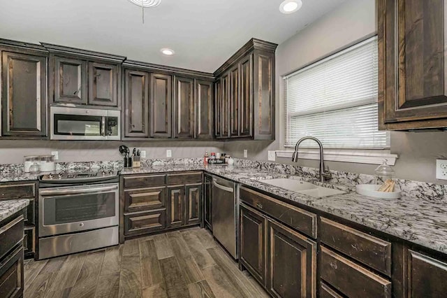 5800 Hester Rd, Amarillo, TX 79124 - kitchen with appliances with stainless steel finishes, a sink, dark brown cabinets, light stone countertops, and dark wood-style flooring