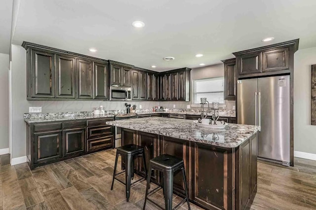 5800 Hester Rd, Amarillo, TX 79124 - kitchen with appliances with stainless steel finishes, baseboards, light stone counters, a center island, and recessed lighting