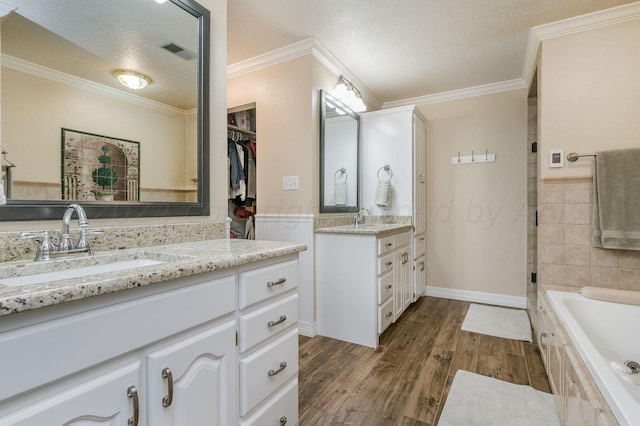 full bath featuring a sink, a textured ceiling, a bathtub, wood finished floors, and visible vents