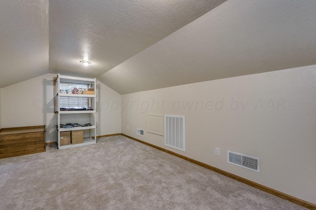 bonus room with a textured ceiling, visible vents, baseboards, and vaulted ceiling