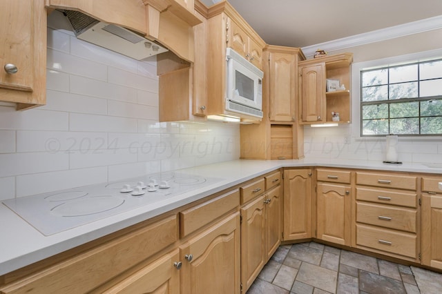 kitchen with white appliances, stone finish floor, backsplash, under cabinet range hood, and ornamental molding