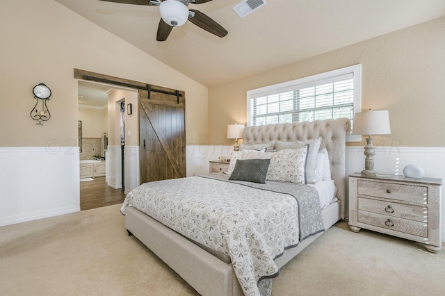 carpeted bedroom featuring ceiling fan, visible vents, a barn door, a wainscoted wall, and lofted ceiling