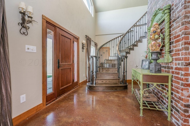 entryway with baseboards, stairs, finished concrete floors, and a towering ceiling