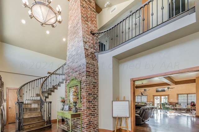 staircase with visible vents, a towering ceiling, wood finished floors, beam ceiling, and ceiling fan with notable chandelier