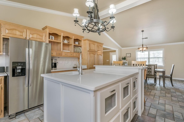 kitchen featuring stainless steel refrigerator with ice dispenser, a center island with sink, a sink, and stone tile flooring