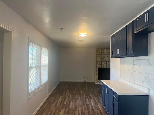 kitchen with blue cabinets, a fireplace, dark hardwood / wood-style floors, and decorative backsplash