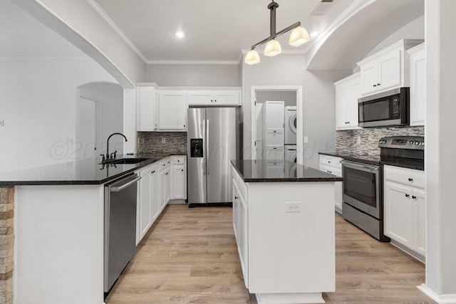 9909 Asher Ave, Amarillo, TX 79119 - kitchen featuring appliances with stainless steel finishes, estacked washer and dryer, a sink, ornamental molding, and a center island