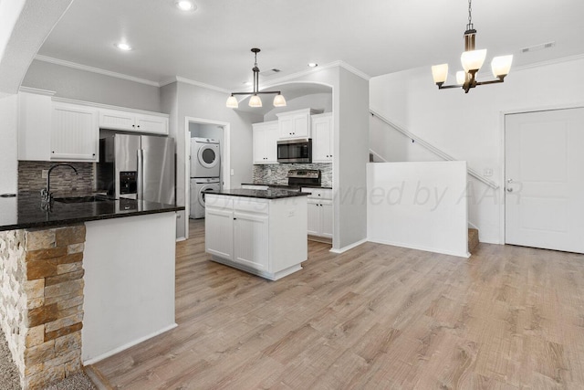 9909 Asher Ave, Amarillo, TX 79119 - kitchen with stainless steel appliances, stacked washer and clothes dryer, a sink, ornamental molding, and backsplash
